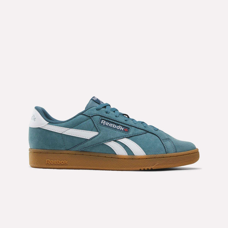Showcased on a plain white background, the Men’s Club C Grounds UK 1.0 Shoes by Reebok feature a Midnight Tide/White colorway with classic suede uppers, signature white side stripes, a white heel tag, and a gum rubber sole—spotlighting timeless Reebok heritage combined with modern comfort.