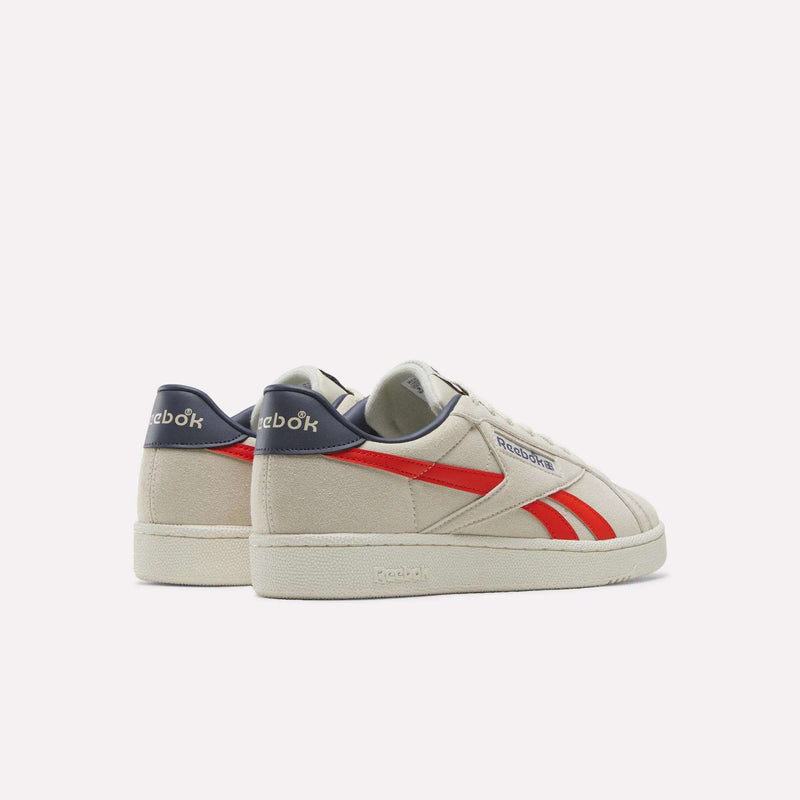 Men’s Club C Grounds UK 1.0 Shoes by Reebok, featuring a beige suede upper with red stripes and navy blue heel accents, inspired by classic Reebok heritage, displayed from the back and side on a plain white background.