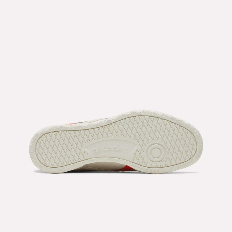 The image shows the off-white sole of the Reebok Men’s Club C Grounds UK 1.0 Shoes, viewed from the bottom, featuring a herringbone tread pattern and the Reebok logo embossed in the center—a classic detail that reflects Reebok heritage. This men’s sneaker exemplifies timeless style and craftsmanship.