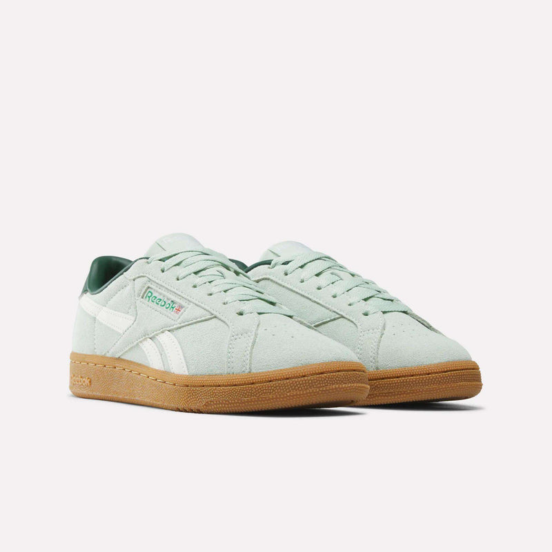A pair of Reebok Women’s Club C Grounds UK 1.0 Shoes in mint green suede, featuring white accents, green lining, and gum soles, displayed side by side on a plain white background.