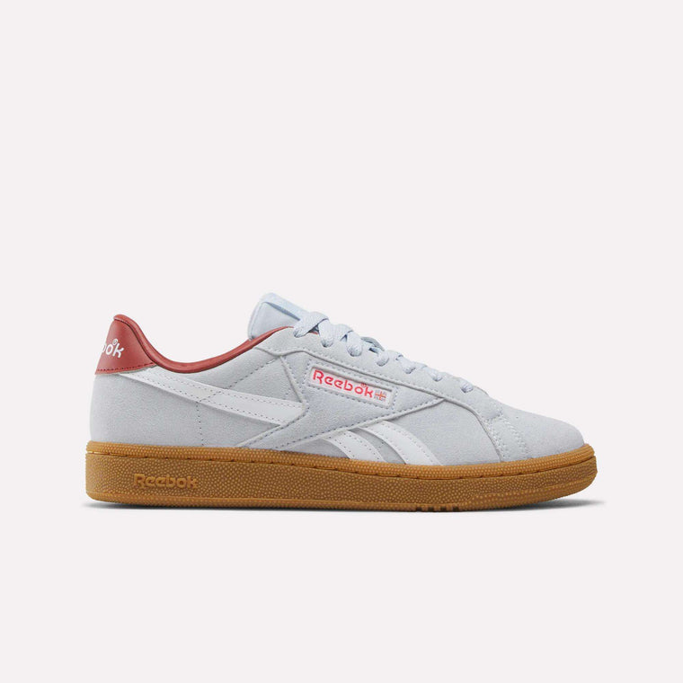 A blue and white Reebok Women’s Club C Grounds UK 1.0 shoe with a classic side stripe, subtle branding, and a brown gum sole is shown in a side profile against a plain white background—an iconic addition to women’s shoes that highlights classic Reebok heritage.