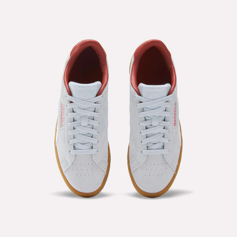 A pair of Women’s Club C Grounds UK 1.0 Shoes by Reebok—featuring a white upper, gum soles, red inner lining, and signature Reebok branding on the sides—are displayed from an overhead view against a plain light background.