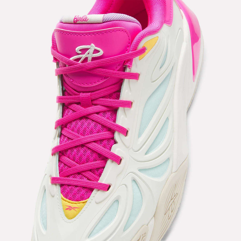 A close-up of a Reebok x Barbie x Angel Reese 1 Shoe showcases its white and light blue upper, vibrant pink tongue, laces, and lining, highlighted by a B logo and yellow accents—these Reebok sneakers are crafted with an advanced Energy Return System for maximum comfort on the court.