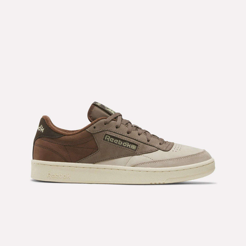 The Men’s Club C 85 Shoes by Reebok feature an Elevated Beige, Trek Grey, and Formal Brown colorway with classic laces, a cream-colored sole, and the signature Reebok logo on the side. These retro sneakers bring timeless style that’s ideal for casual footwear enthusiasts. The shoes are displayed against a simple, light background.