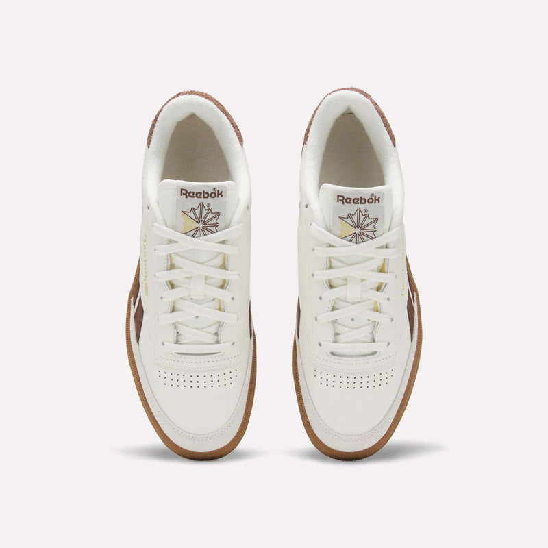 Top view of a pair of Men's Club C Revenge Vintage Shoes by Reebok, in white leather with brown soles and accents, showcasing the Reebok logo and starburst design on the tongue against a plain light background.