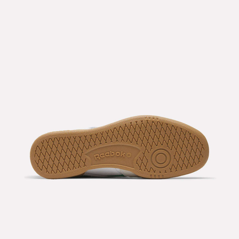 The image shows the bottom sole of the Reebok Men's Club C Revenge Vintage Shoes, featuring a tan rubber surface with a herringbone tread pattern and embossed Reebok branding, underscoring its classic heritage style.