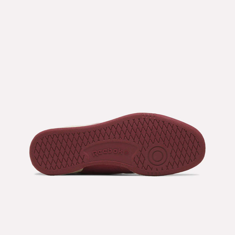 The maroon sole of the Reebok Men’s Club C 85 Shoes is shown from the bottom, featuring the Reebok logo, textured grip patterns, and a circular design near the heel—an iconic element often found in men’s tennis footwear crafted with premium materials.