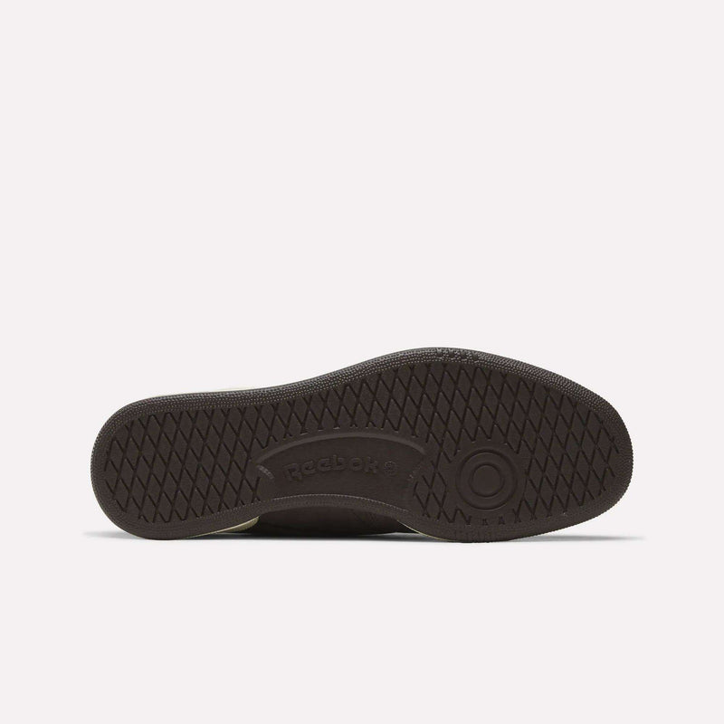 The image shows the sole of a dark Men's Club C 85 Shoe by Reebok, featuring a textured crisscross pattern, a circular toe design, and the embossed Reebok logo at the center.