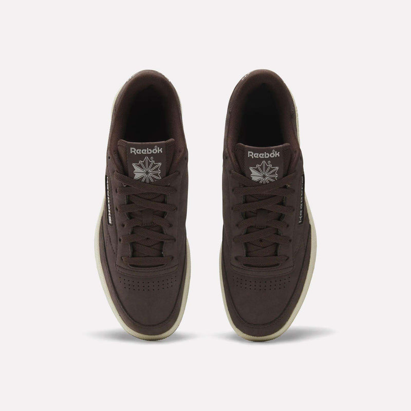 Top view of Reebok Men's Club C 85 Shoes in dark brown nubuck leather with off-white soles and visible logos on the tongue and side, displayed against a plain white background.