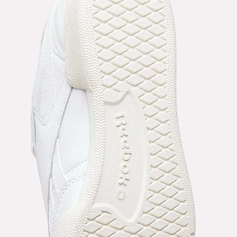 Close-up of the sole of a white Men’s Club C Revenge Shoe by Reebok, highlighting the textured grip pattern and the embossed Reebok logo at the center, showcasing its classic tennis-inspired design.