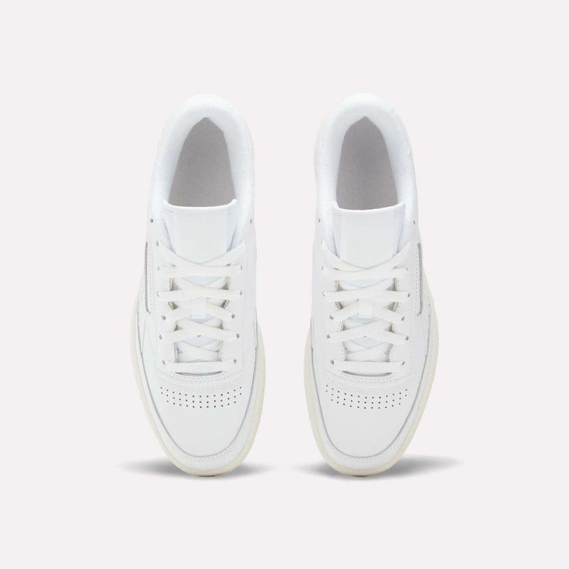 A pair of Reebok Men’s Club C Revenge Shoes is displayed from an overhead perspective on a simple light background. These Reebok sneakers, inspired by classic tennis style, showcase white laces, perforated toe boxes, and subtle details.