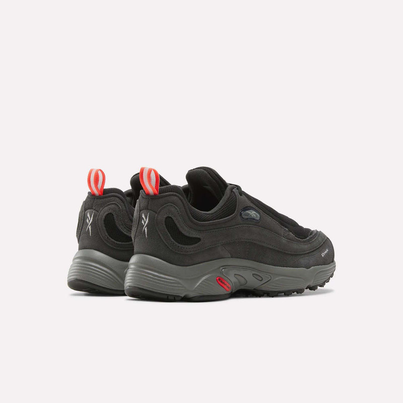 A pair of Men’s Daytona DMX Shoes by Reebok in black with thick gray soles featuring air cushioning, red heel loops, and white Reebok logo details on the heel, shown from the back and slightly to the side against a plain background.