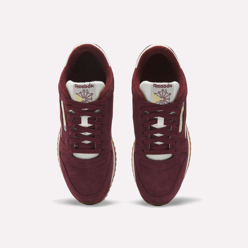 A pair of Reebok Men’s Classic Leather Ripple Shoes in maroon are shown from above, highlighting white tongues adorned with the Reebok logo and a stylized star graphic. These sneakers feature the iconic Classic Leather Ripple design and a comfortable EVA midsole.