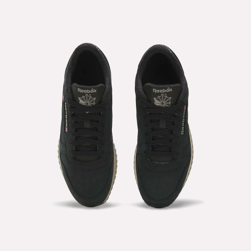A top view of the Men’s Classic Leather Ripple Shoes by Reebok, featuring black uppers with matching black laces, white Reebok branding on the tongue and side, a comfortable EVA midsole, and tan ripple outsoles, displayed against a plain light background.