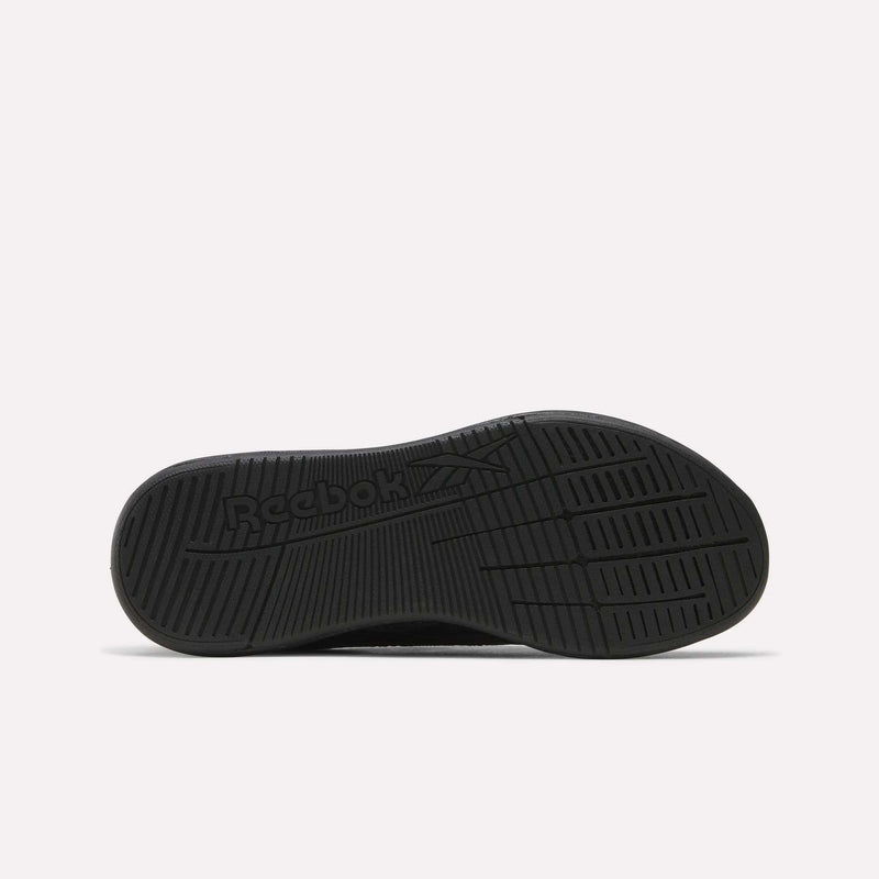The image displays the black rubber sole of the Women’s Nano X5 Training Shoes by Reebok, viewed from underneath. The tread pattern features parallel grooves, and the Reebok logo with its vector symbol is embossed near the heel, emphasizing optimal comfort and traction for any workout.