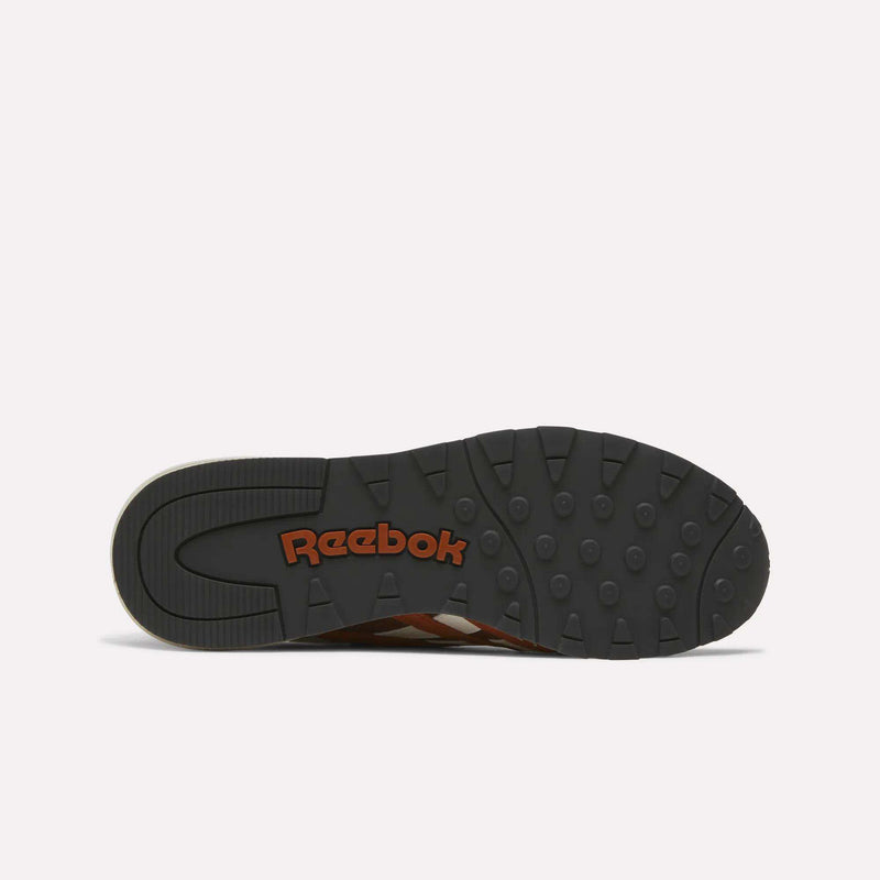 The black rubber outsole of the Men’s Classic Nylon 89 Shoes by Reebok is pictured from underneath, displaying round traction bumps along with the orange Reebok logo. These mixed-material sneakers feature an EVA midsole for lightweight cushioning and lasting comfort.