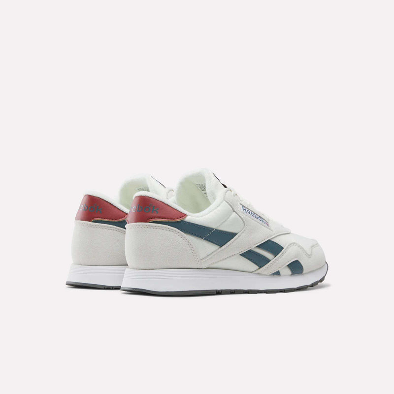 A pair of Men’s Classic Nylon Shoes by Reebok in white, featuring blue stripes and red accents, crafted from mixed materials with an EVA midsole, is displayed from the back and side against a plain light background.