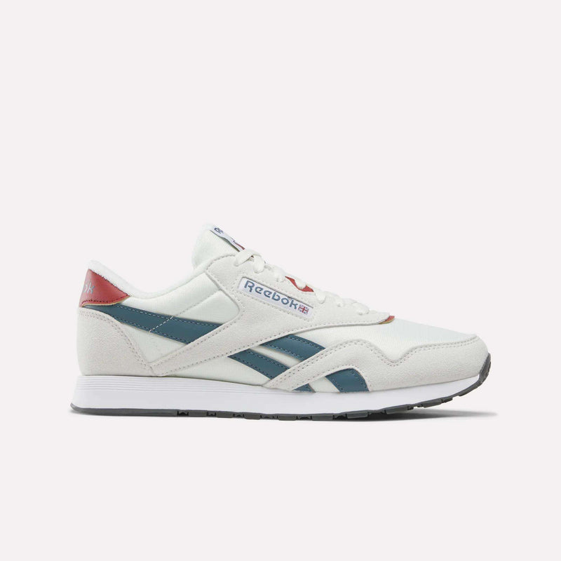 A pair of Reebok Men’s Classic Nylon Shoes in Chalk/Heritagered/Midnighttide is displayed in a side profile view against a plain white background. These mixed material sneakers showcase teal and red accents, blue side stripes, a white sole, and feature an EVA midsole for enhanced comfort.