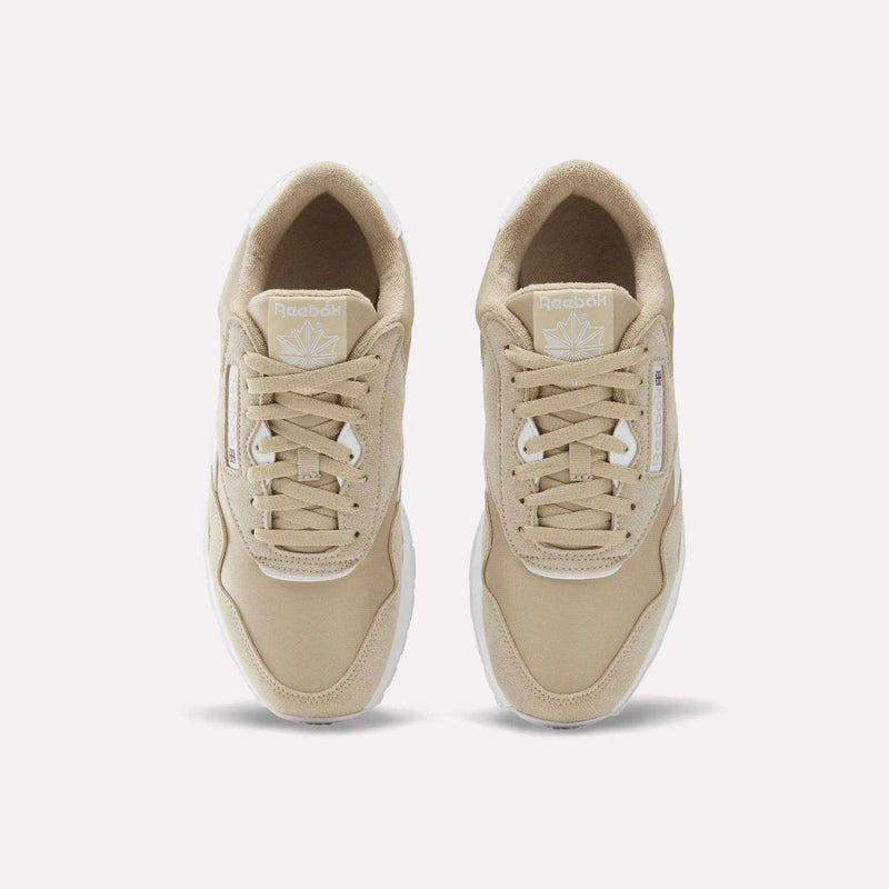 A pair of Reebok Men’s Classic Nylon Shoes in beige, viewed from above, displaying their laces, white soles, and signature Reebok branding on the tongue and side—ideal men’s footwear for a timeless look.