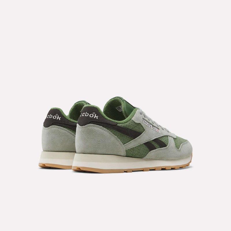A pair of Reebok Men’s Classic Leather Shoes in green and light gray, featuring white EVA midsoles and gum outsoles, shown from a back side angle on a plain white background.