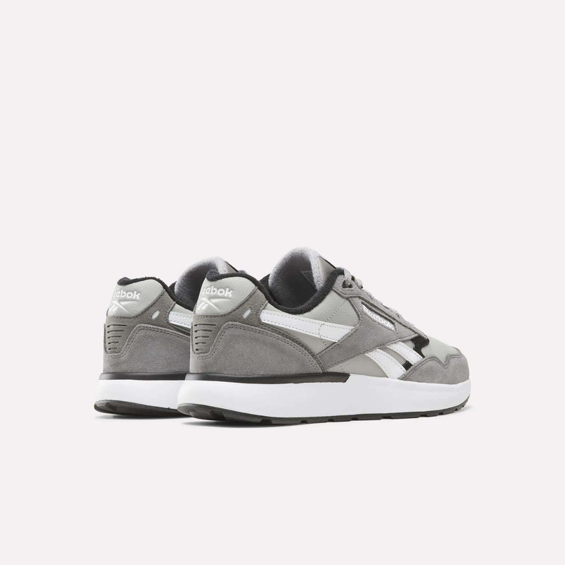 A pair of Reebok Men’s Run LXS Shoes in gray and white rest on a white background, with one shoe facing forward and the other angled to display the heel and side logo. Crafted from full-grain leather, these retro-inspired running shoes combine classic style with lasting durability.