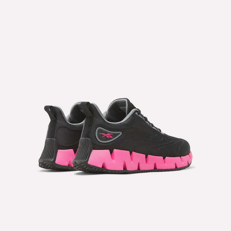 Black Reebok Women’s Zig Futaura 1.0 running shoes with a mesh upper and bright pink zigzag-patterned soles.
