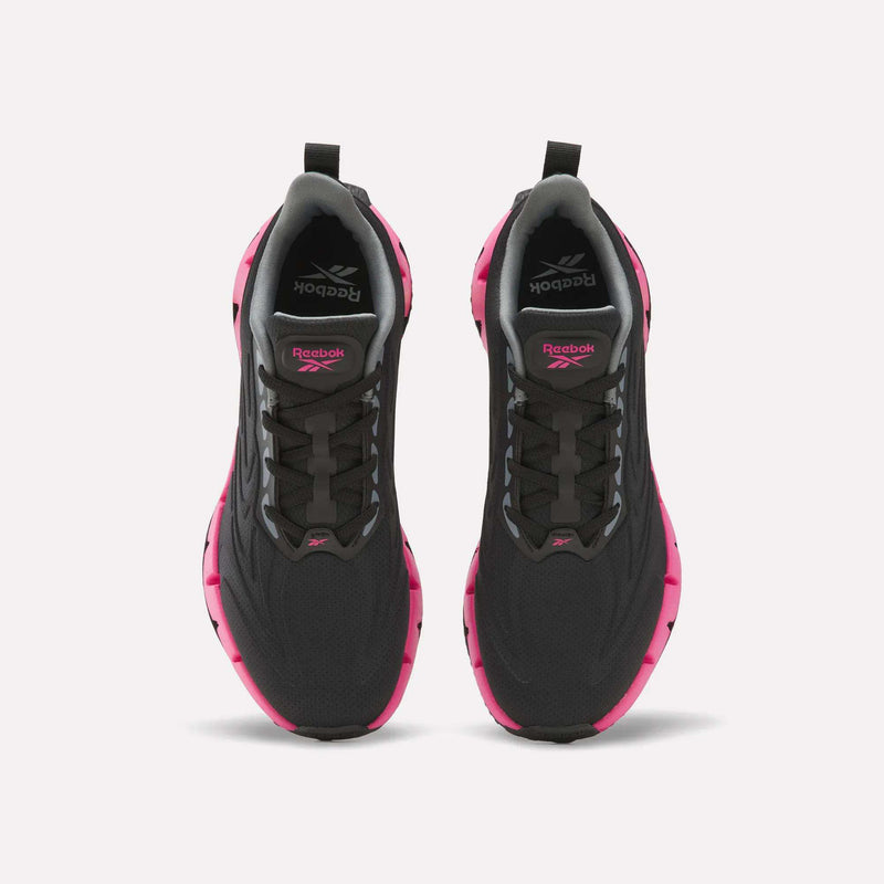 Pair of black Reebok Women’s Zig Futaura 1.0 Shoes with bright pink zigzag-patterned FuelFoam midsoles, viewed from directly above.
