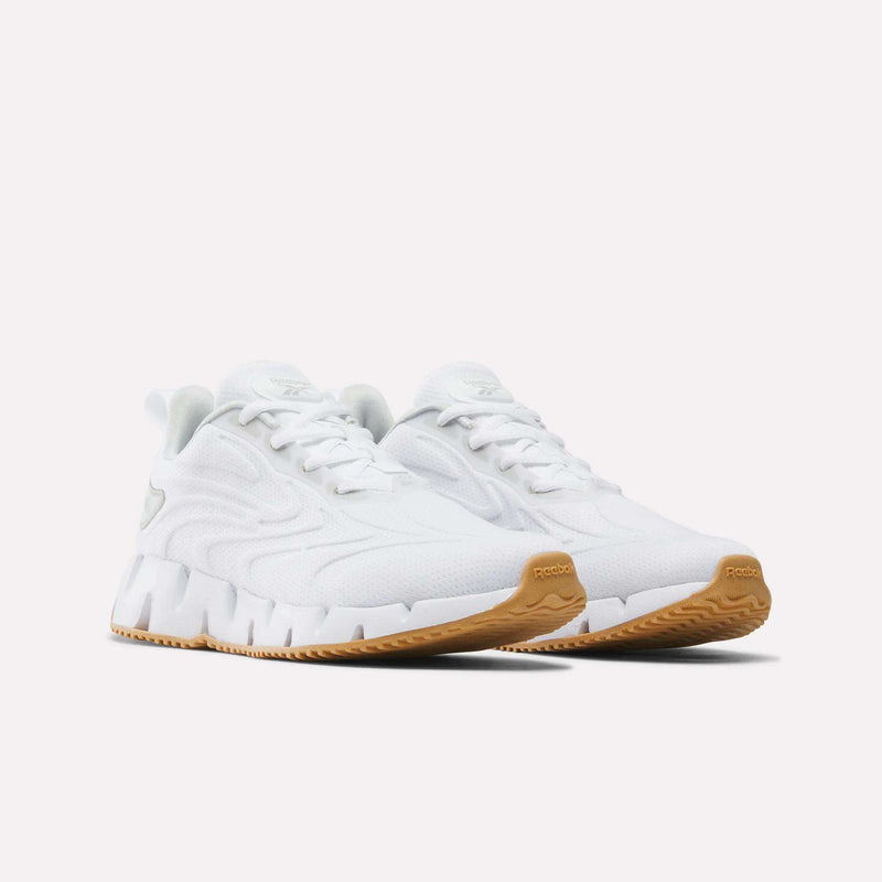 Women’s Zig Futaura 1.0 Reebok running shoes in white, featuring a breathable mesh upper, a thick, zigzag-patterned FuelFoam midsole, and a tan rubber outsole.