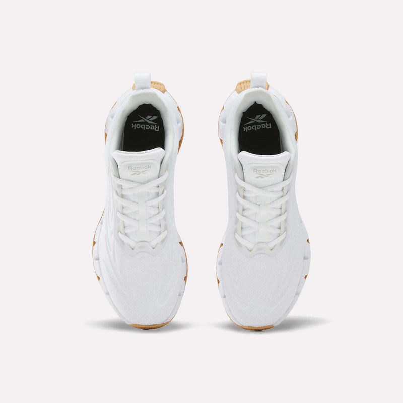 Top-down view of white Reebok Women’s Zig Futaura 1.0 shoes with mesh uppers, textured FuelFoam midsoles, and tan heel accents.