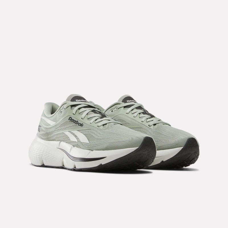 A pair of Reebok Men’s Zignition Running Shoes in light green, featuring white accents, black soles, and a breathable mesh upper with a wide forefoot and springy cushioning—displayed against a plain white background.