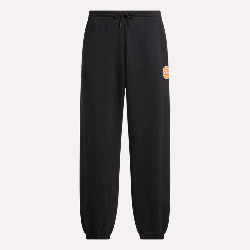 The Reebok Men's Pump OG Joggers feature an elastic waistband and cuffs, a drawstring, and a small orange circular logo on the left thigh. Inspired by the classic Reebok Pump with a subtle retro graphic, these jogger pants are displayed on a plain, light background.