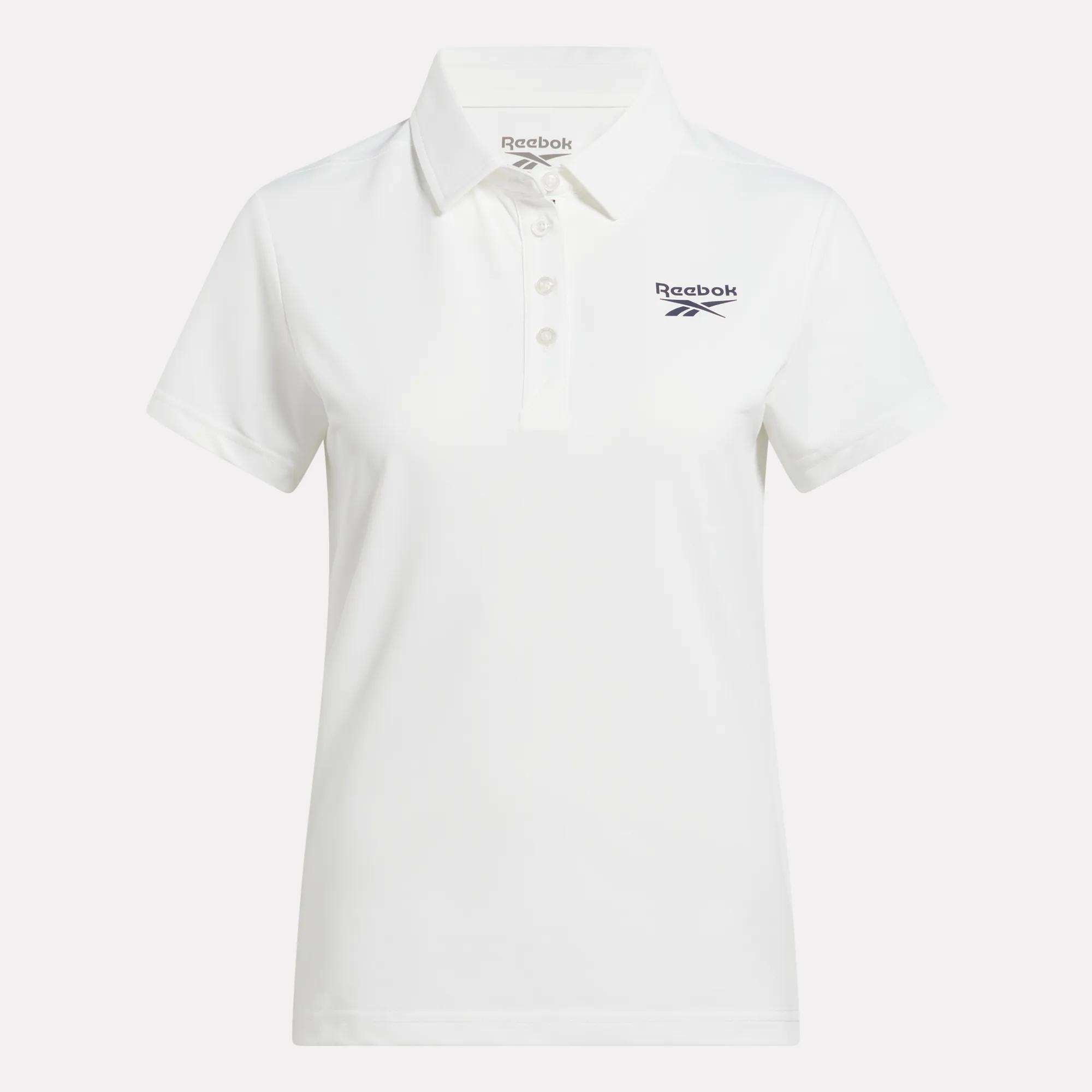 The Reebok Women's Micro Pique Polo Shirt is a white, short-sleeve collared polo with three buttons and a navy Reebok logo on the left chest. Made from stretch fabric for comfort and easy movement on the golf course.