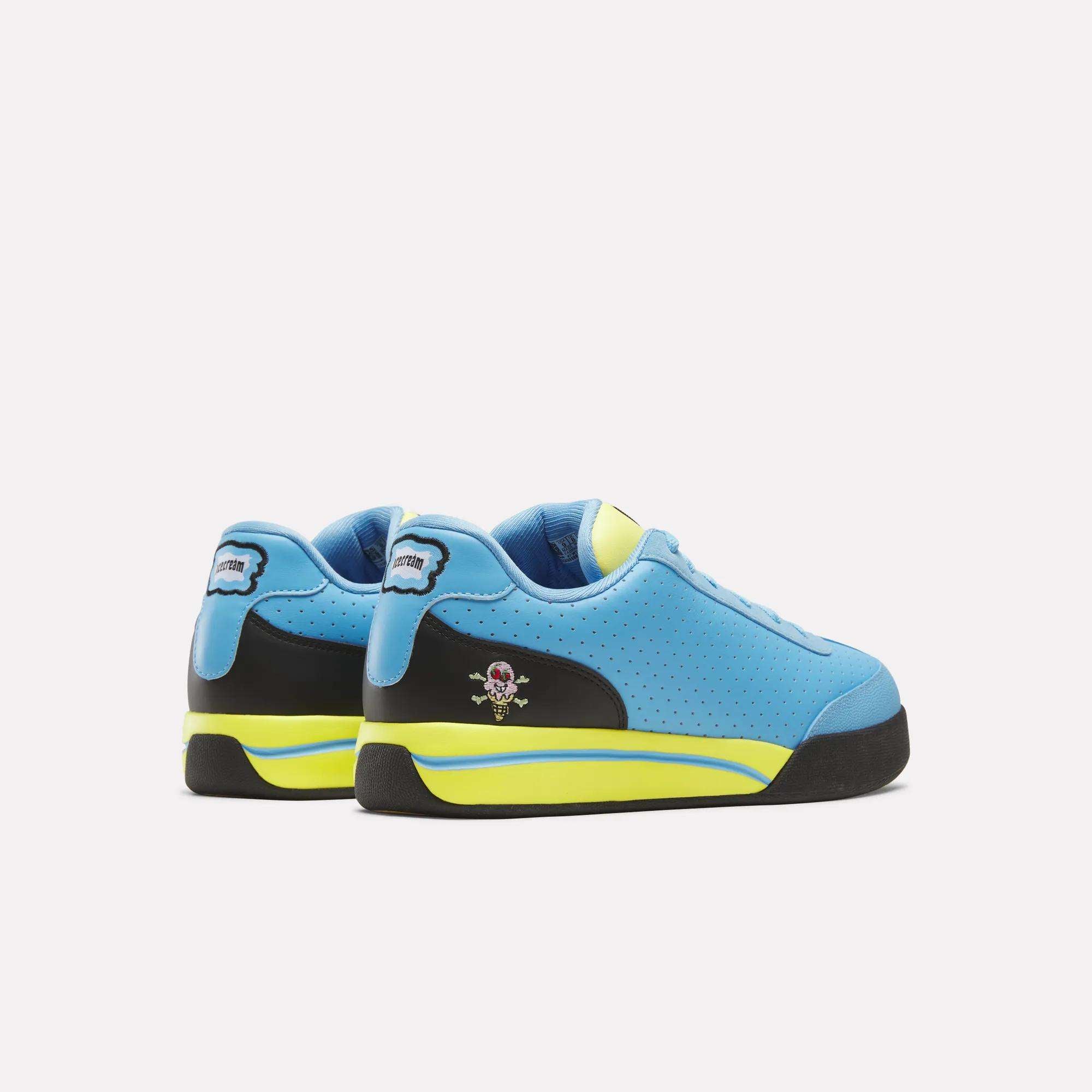 The Reebok x Icecream Board Flip Shoes by Reebok are blue sneakers with black, yellow, and neon green accents, early-2000s skate style, a small skull and crossbones on the side, and a perforated upper pattern.
