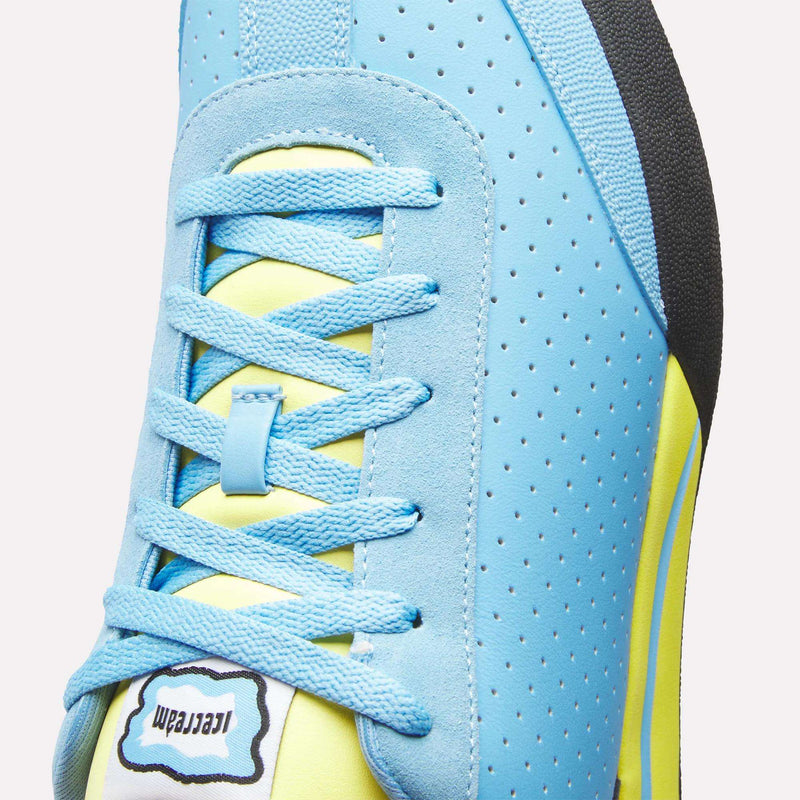 Close-up of Reebok x Icecream Board Flip Shoes in light blue suede with yellow accents, blue laces, perforated leather details, a black, white & yellow Reebok x Icecream tongue label, and a black heel.