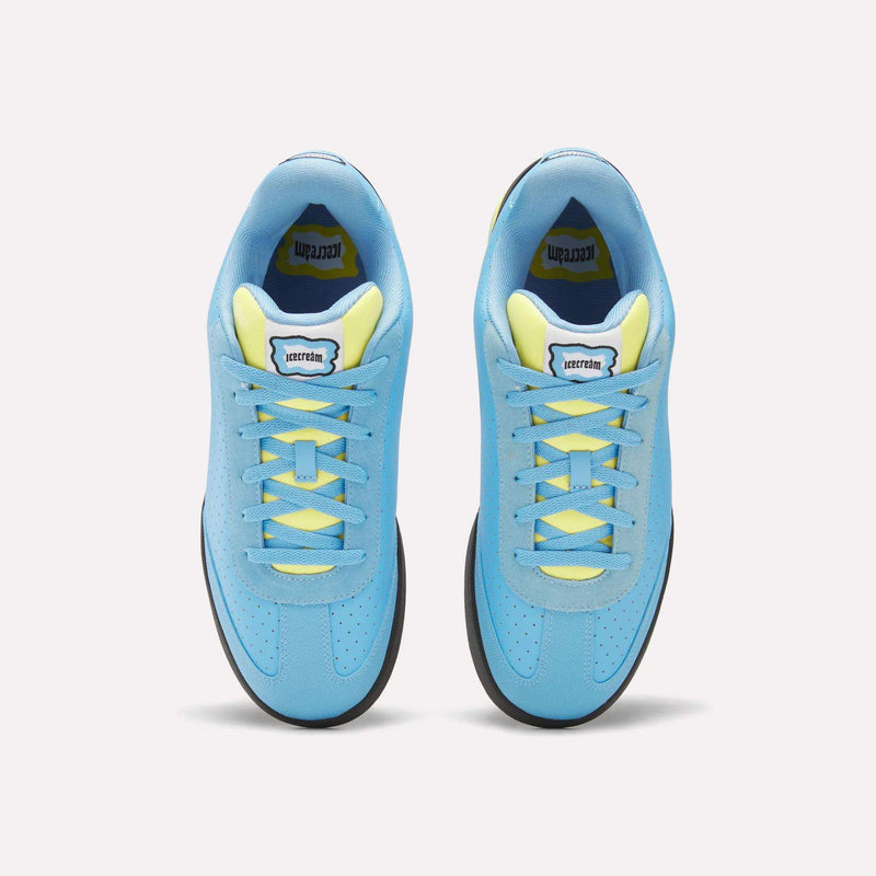 A pair of Reebok x Icecream Board Flip Shoes in blue with yellow laces and inner lining, seen from above on a light background. Early-2000s style sneakers feature a rectangular tongue label with black text.