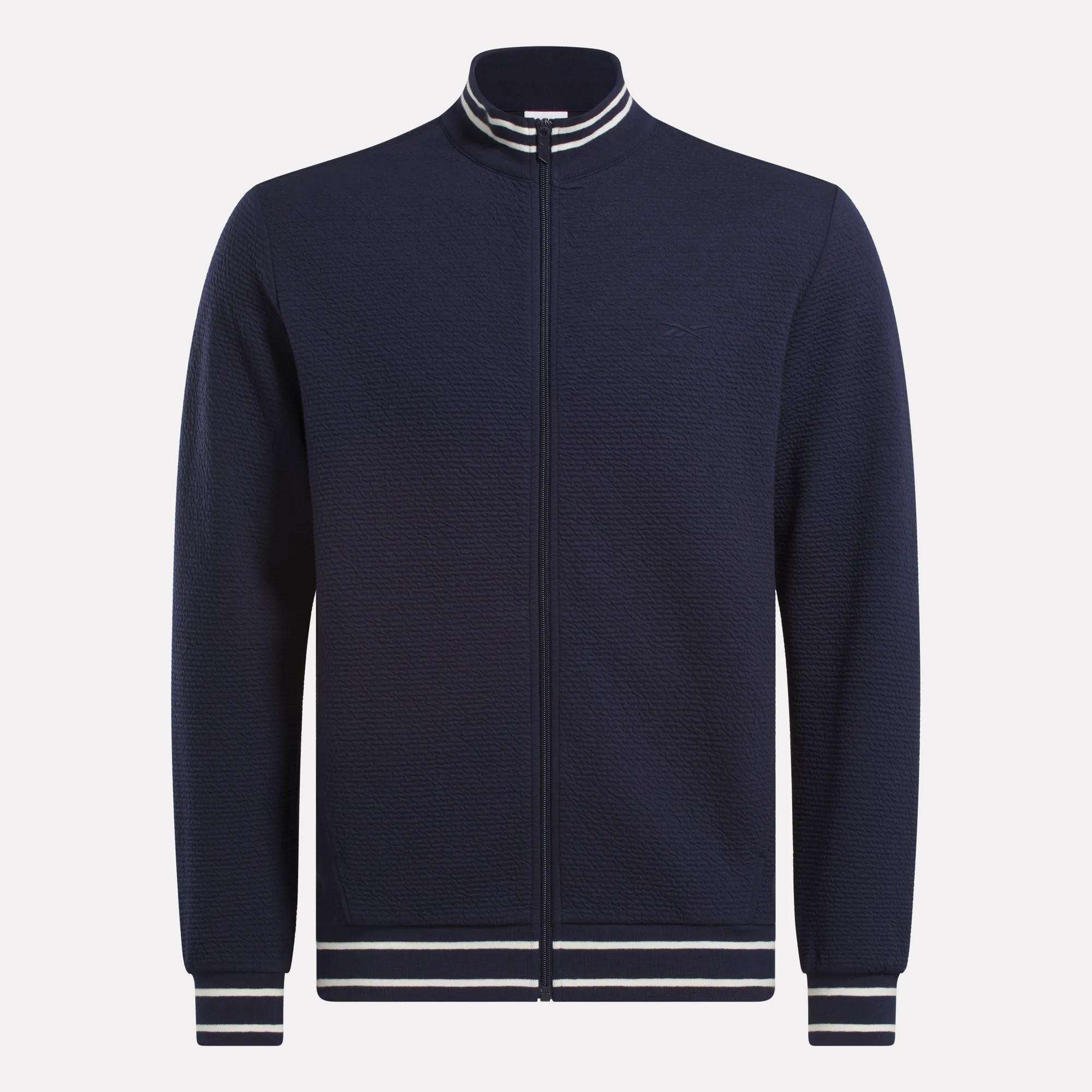 The Reebok Men's Club Sport Textured Jacket is a navy zip-up with thermal knit fabric and white/navy striped ribbed collar, cuffs, and hem, shown on a plain white background.