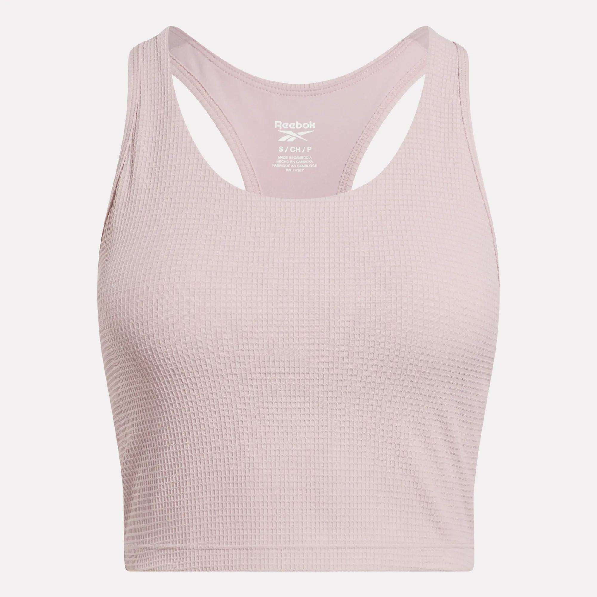 The Reebok Women's Time Out Cropped Tank Top in light pink features a ribbed pattern and racerback design—perfect for stylish activewear. Shown against a plain white background.