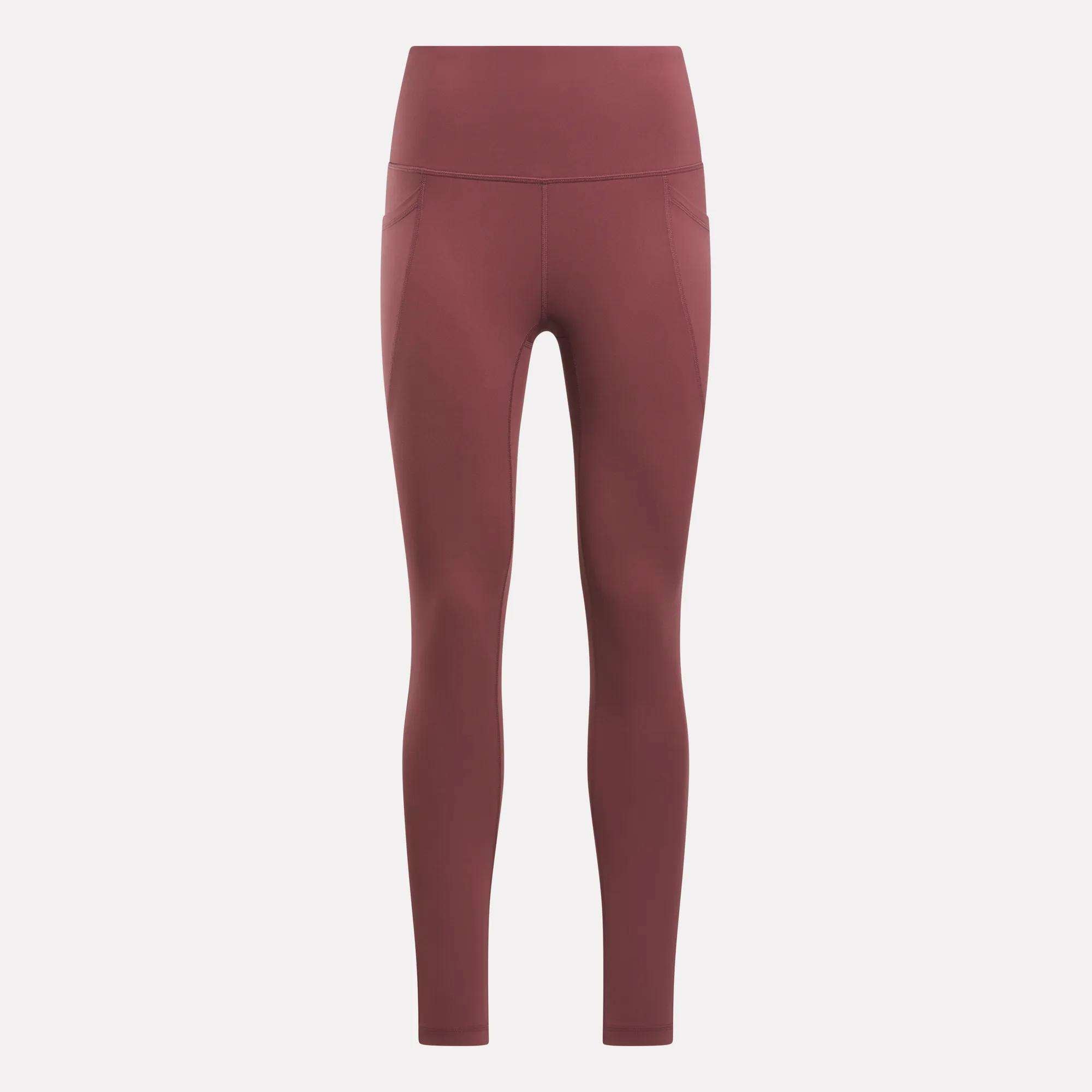 Reebok Women's High-Rise Tights in a muted reddish-brown feature side pockets, visible seam details, and a high-rise waistband. These full-length training tights are displayed on a plain light background.