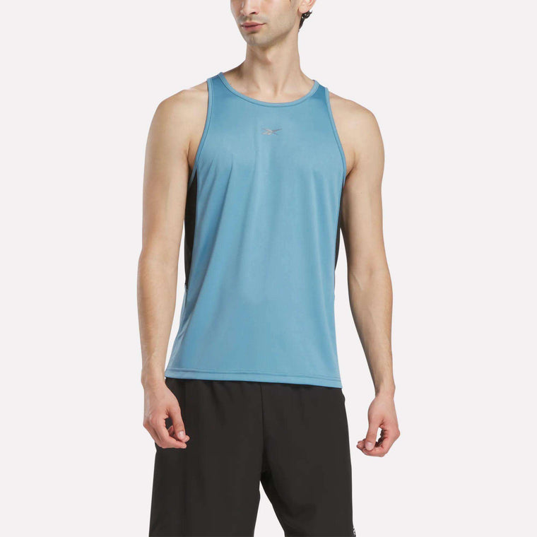 A man wears a Reebok Men's Run Speedwick Singlet and black shorts, standing against a plain white background.