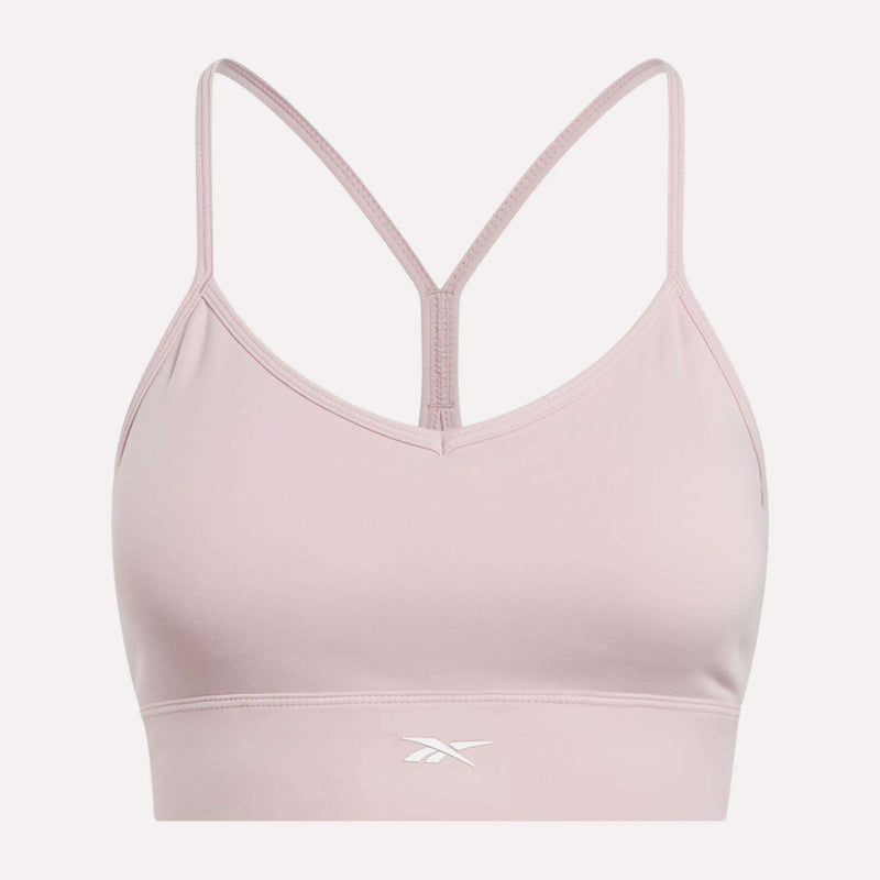 The Reebok Women's Back Bra is a light pink sports bra featuring thin spaghetti straps, a racerback design, medium-impact support, and a small white Reebok logo on the front band. The background is plain white.