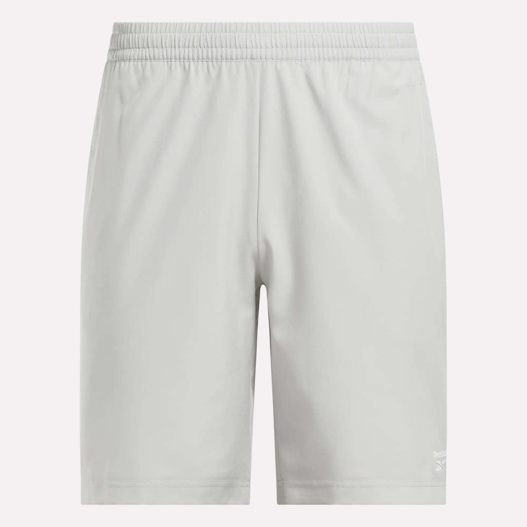 Light gray Reebok Men's Range Shorts 9" with an elastic waistband, shown from the front. These gym shorts have a simple design and a small white Reebok logo near the bottom hem on the left leg.