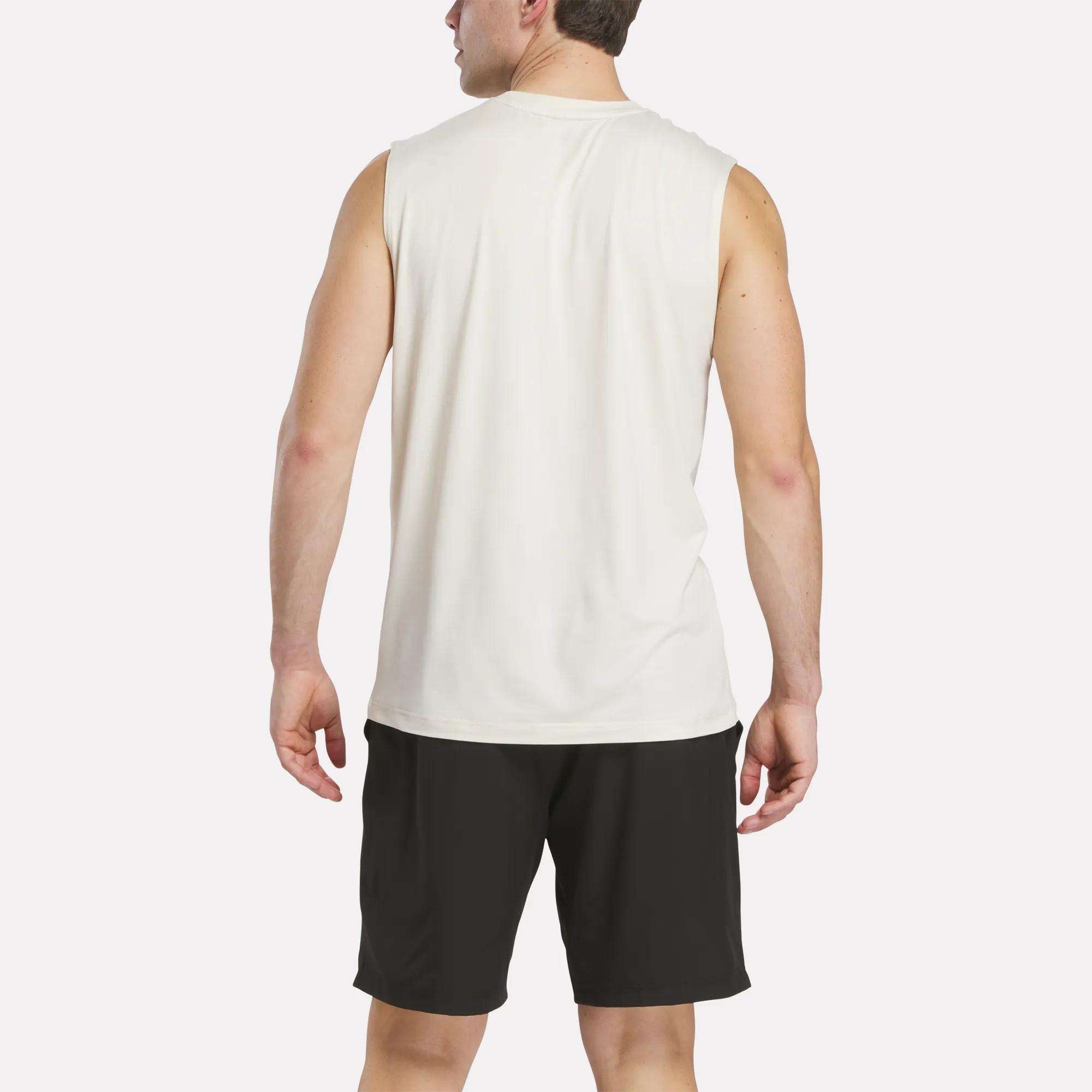 A man stands with his back to the camera, wearing a Reebok Men's Elite Sleeveless Top and black shorts against a plain white background.