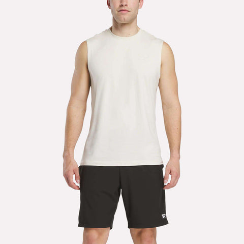 A man faces forward wearing a Reebok Men's Elite Sleeveless Top and black athletic shorts against a plain white background.