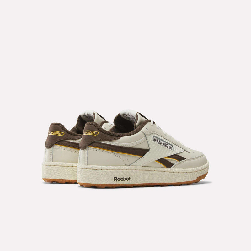 A pair of Reebok x Manors Club C Revenge Golf Shoes in beige with brown and yellow accents, showcasing MANORS branding and a gum sole, displayed on a white background.