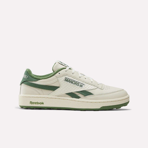 The Reebok x Manors Club C Revenge Golf Shoes showcase a Vintage Chalk, Legacy Green, and Linen colorway with distinctive Manors branding. This classic low-top silhouette features green accents on the sole, laces, and heel, all expertly presented against a clean white background.