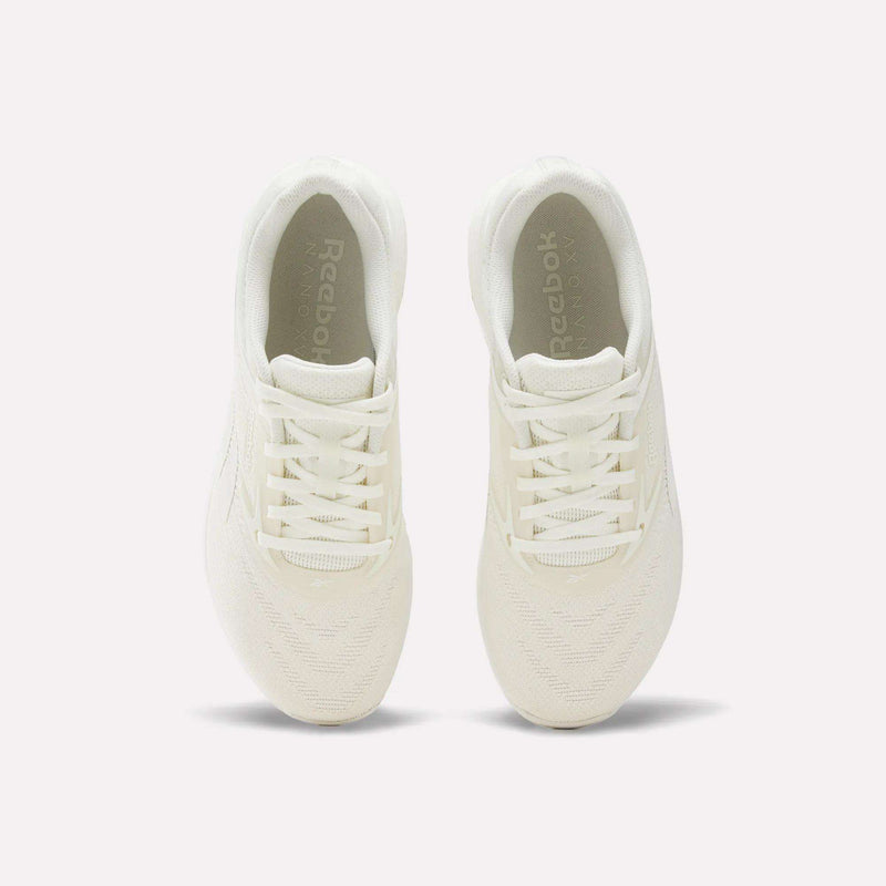 A pair of Reebok Nano X5 Training Shoes in white, photographed from above to display the tops, laces, and insoles with the Reebok logo visible inside each shoe. Designed with a dual-density midsole for enhanced support and comfort, these sneakers are ideal for your next workout session. The background is plain and light-colored.