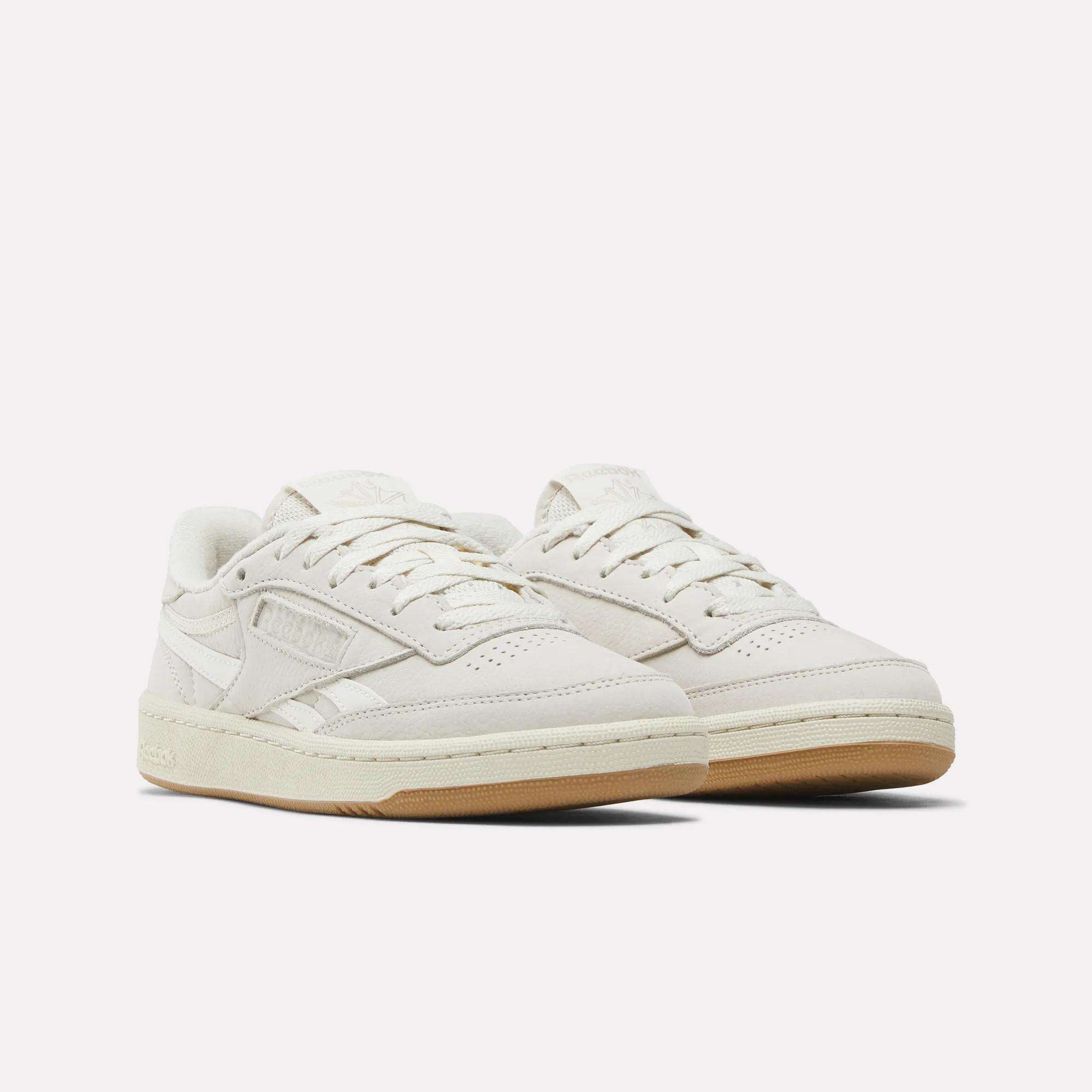 The Reebok Women's Club C Revenge Shoes feature an off-white nubuck leather upper, low-top design, perforated toe, side logos, and light tan rubber soles, shown against a plain white background.