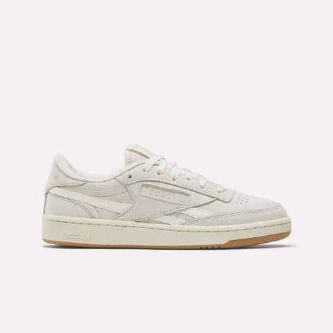 The Reebok Women's Club C Revenge Shoes feature a beige low-top design with a suede and nubuck leather upper, beige laces, and a light brown rubber sole, displayed in side profile on a plain white background.