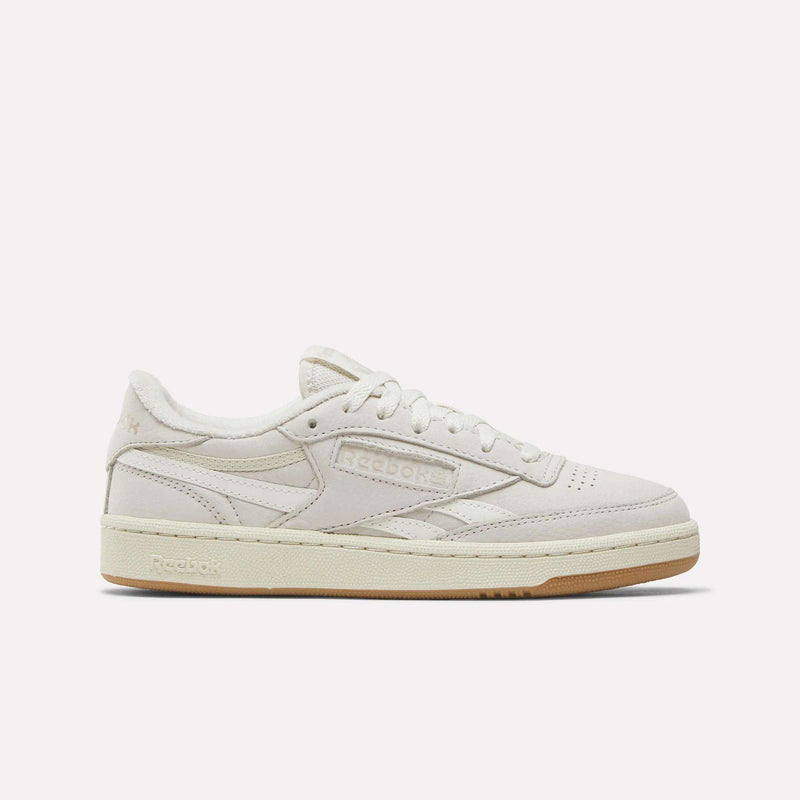 The Reebok Women's Club C Revenge Shoes feature a beige low-top design with a suede and nubuck leather upper, beige laces, and a light brown rubber sole, displayed in side profile on a plain white background.