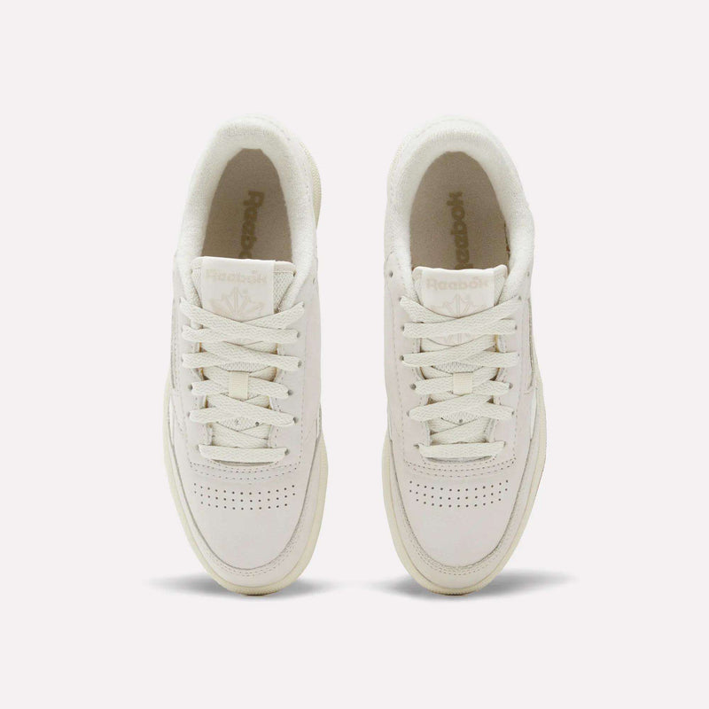 A pair of Women's Club C Revenge Shoes by Reebok in white, seen from above with visible laces, perforated toe areas, and Reebok logos on both the tongue and insole.